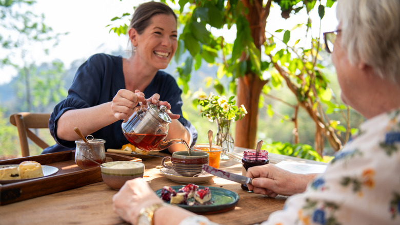 Elegantly dressed women enjoying tea outdoors