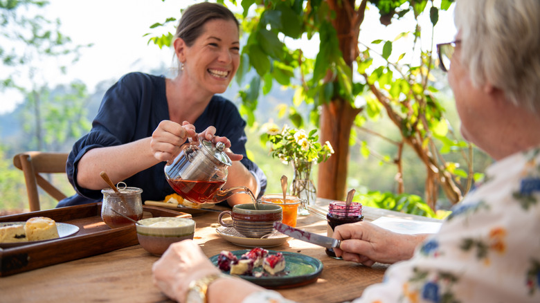 Elegantly dressed women enjoying tea outdoors