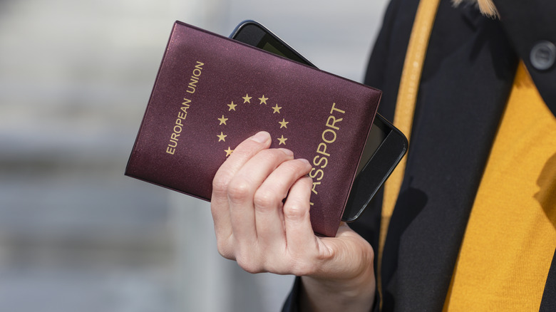 Close-up image of woman holding an EU passport and phone