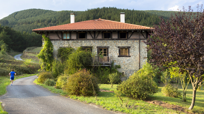 View of a runner passing by a pretty casa rural in the Basque region of northern Spain