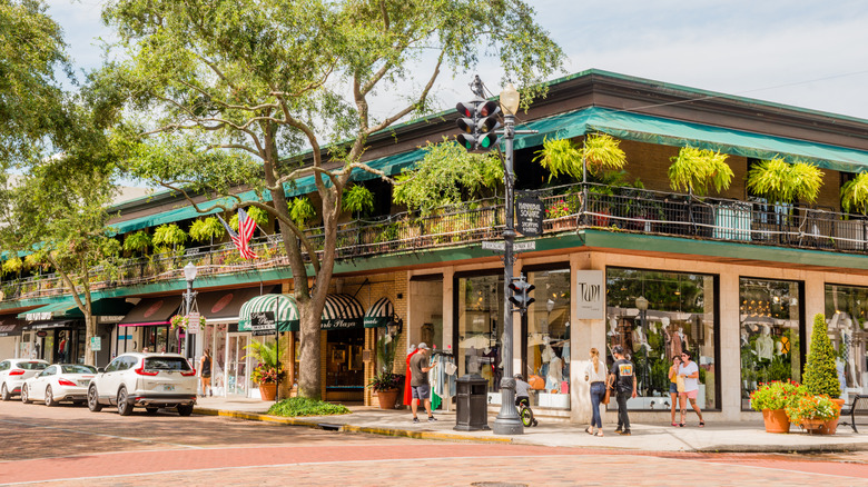 Corner of Park Avenue in Winter Park showing stores, balconies of Park Plaza Hotel and green trees lining the street.