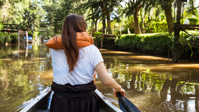 woman in life vest rows down Tigre river canal