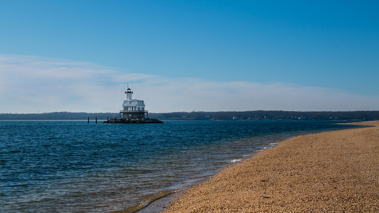 a gravely beach with the Orient Point lighthouse in the background