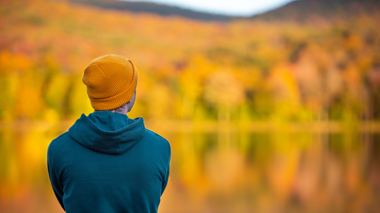 hiker gazing at orange fall foliage