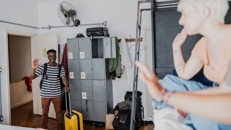 Tourists in a backpacker hotel with lockers and bunk beds.