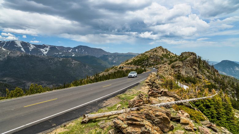 a car driving on narrow highway pass along a steep mountain