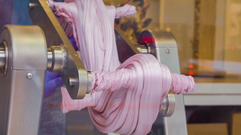pink gooey taffy getting stretched and mxied by a machine