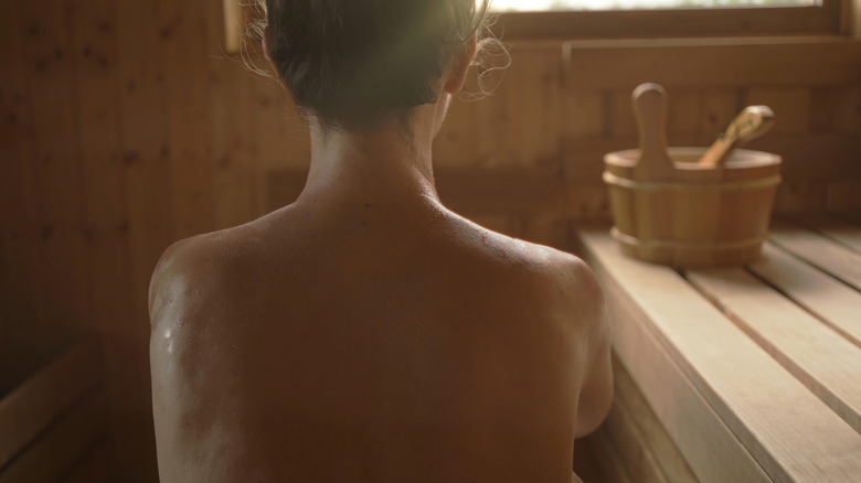 The back of a woman sitting in a sauna with no bathing suit on