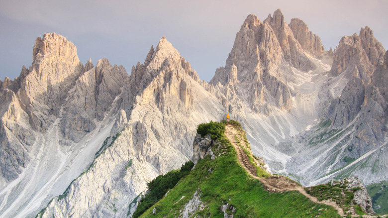 A person in a yellow jacket stands atop Cadini di Misurina, near the mountains of Tre Cime di Lavaredo in the Dolomites, Italy
