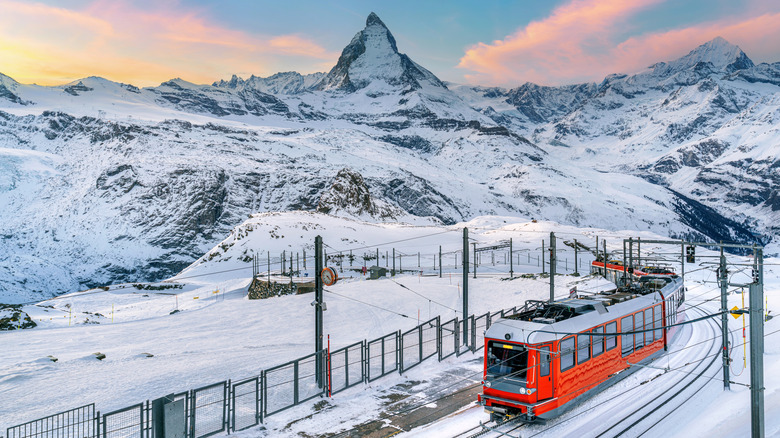 Snowy view of the Matterhorn mountain and a red train in Switzerland