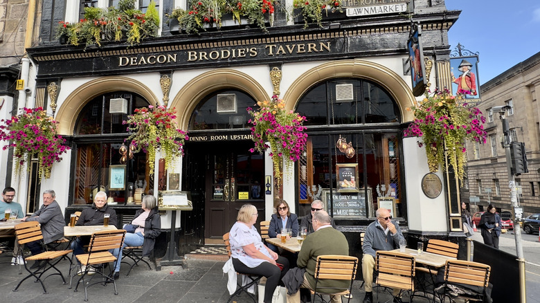 Tourists sitting on the terrace in front of Deacon Brodie's Tavern in Scotland