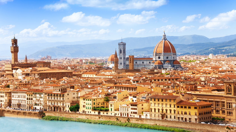An aerial view of the Arno River and the terracotta rooftops of Florence, Italy