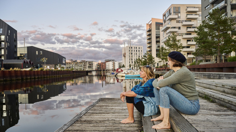 Female couple sitting by the water in Denmark