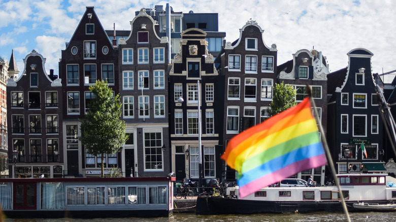 Pride flag with Amsterdam canal houses in the background