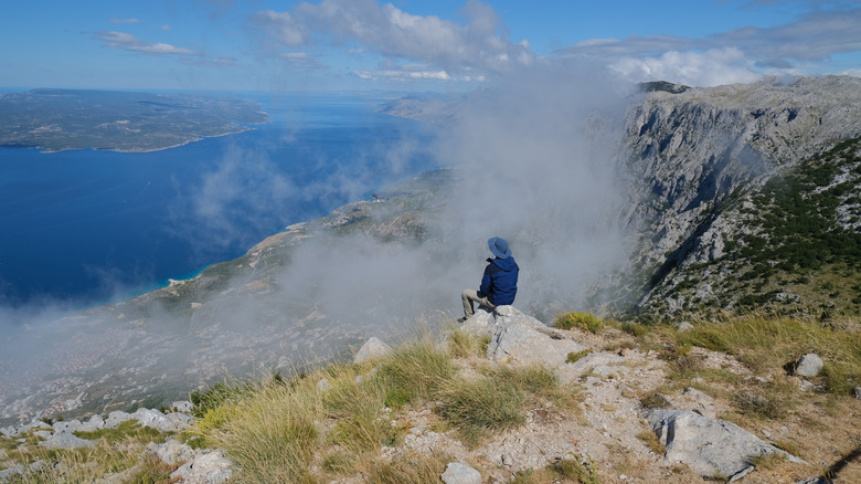 A hiker sitting on a ledge on the island of Brac, Croatia
