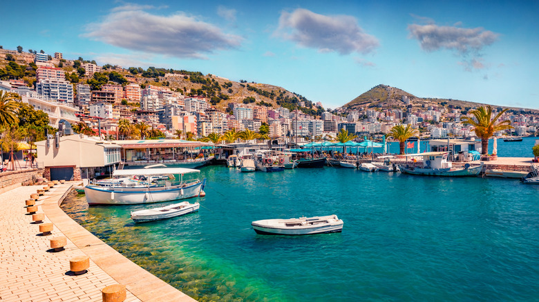 Coastal city of Saranda, with boats docked on the blue waters, and buildings on hills in the background
