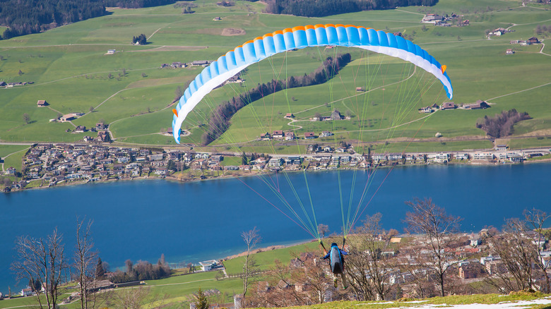 Backview of a paraglider overlooking lakes, fields, and houses in Zurich