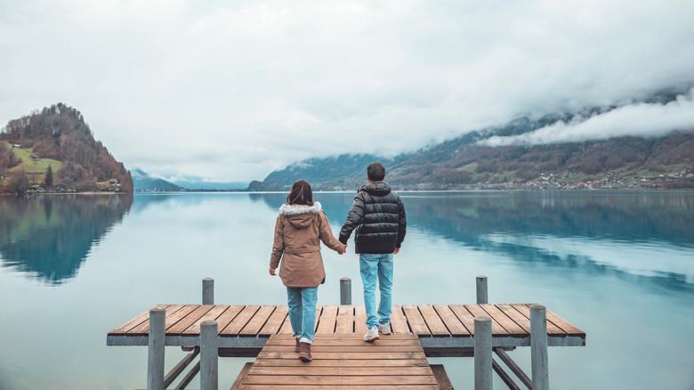 A couple holding hands on a dock overlooking a lake in Switzerland