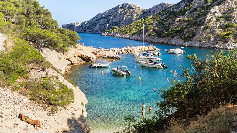 Tourists sunbathing in the boat-filled Calanque de Morgiou