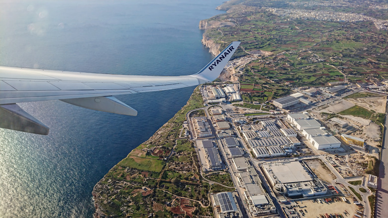 plane wing flying over Malta International Airport