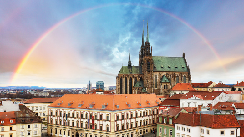 A rainbow arcs over the historic buildings and stone church in the city of Brno, Czech Republic