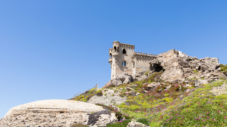 Historic sandstone building on a verdant hill in Tarifa, Spain