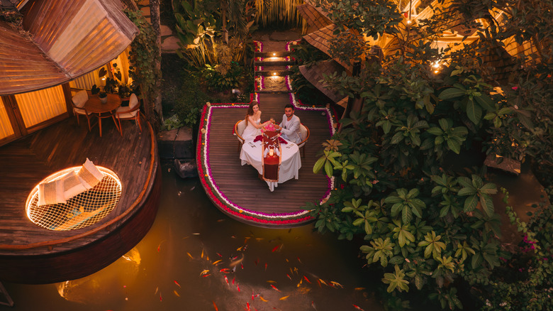 A couple enjoying a private dinner on a floating deck, at Ulaman Eco Luxury Resort in Bali, Indonesia