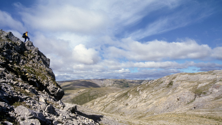 a hiker looking out at the British Mountains in Vuntut National Park from the top of a mountain hike