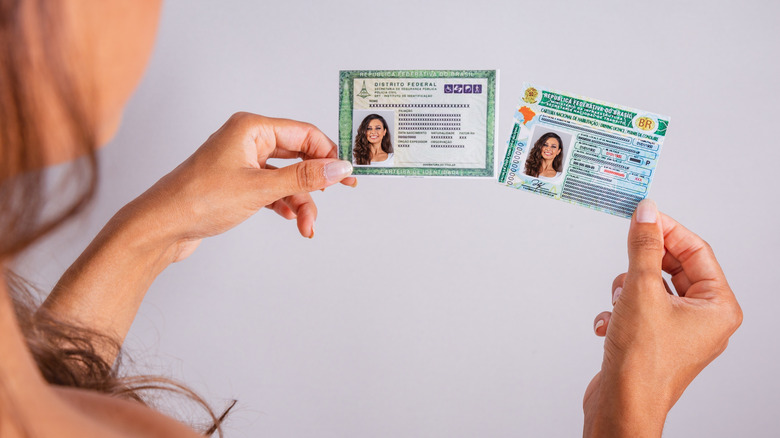 A woman holding a license and other identification