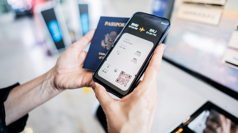A passport and digital plane ticket in a person's hands