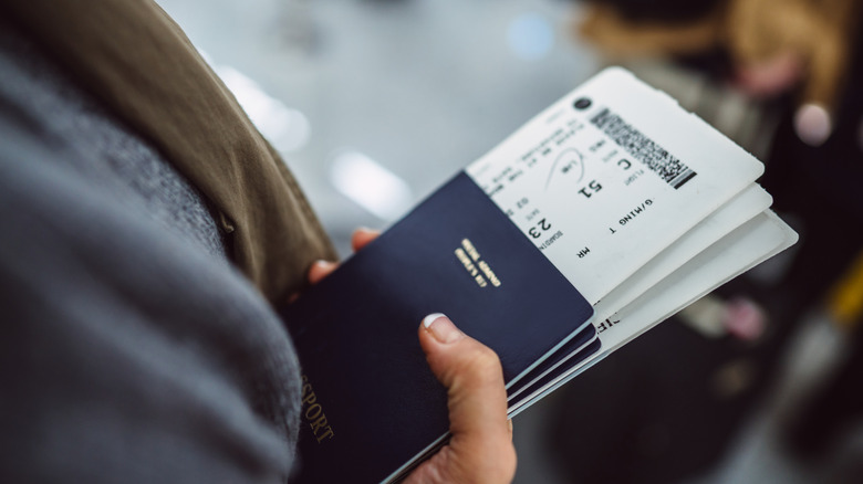 Hand holding plane tickets and passport