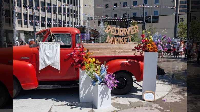 The Red River Market sign with a red truck and flowers