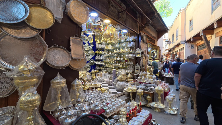 Platters and teapots line stall on busy street in Fes, Morocco