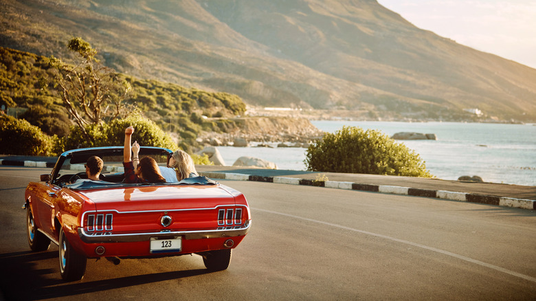 A red convertible on a coastal highway