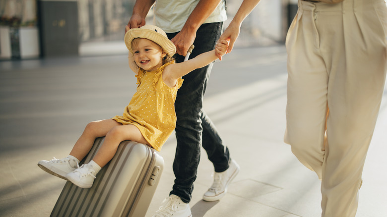 Little girl riding through the airport on a suitcase