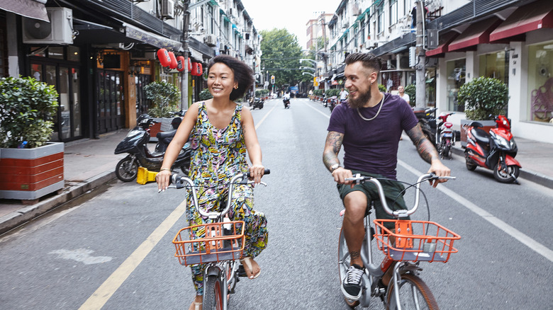 A mixed couple riding their bikes down a typical Shanghai street.