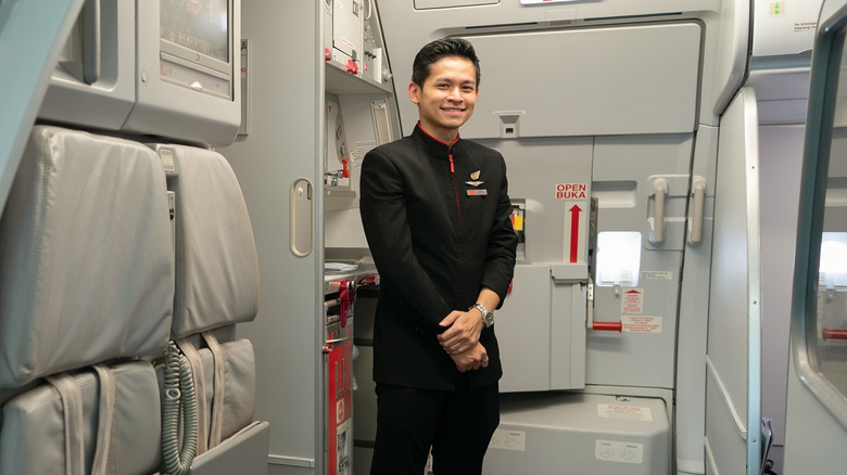 A flight attendant greeting passengers at the door