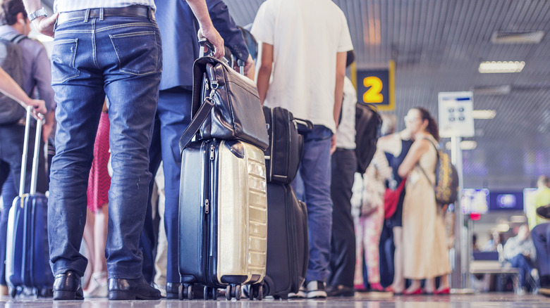 A crowd of people wait to board their plane in an airport terminal