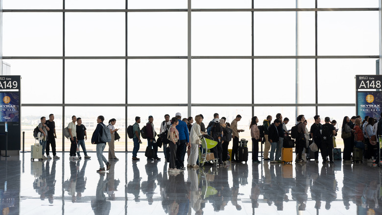 A crowd of passengers near the departure gate at an airport