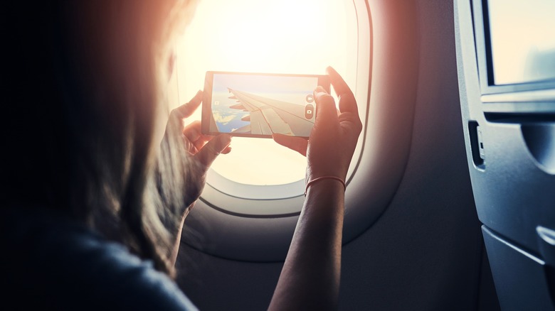 airplane passenger uses phone to take a photo
