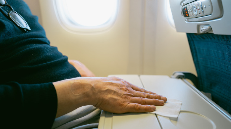 Airline passenger wipes down tray table
