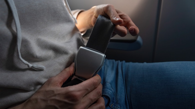 Airplane passenger fastens seatbelt