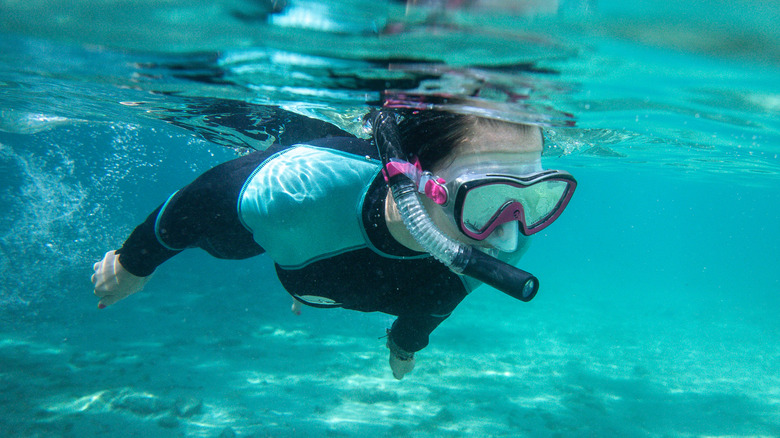 Person snorkeling in crystal-clear blue water