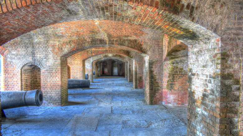 Cannons line a brick hallway with stone floors