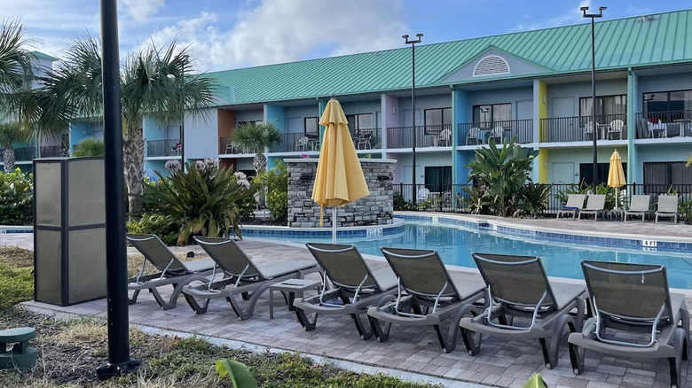 View of lazy river area lined with deck chairs and guest room building in background at Beachside Hotel & Suites in Cocoa Beach, Florida