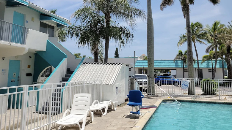View of Hollywood Beachside Boutique Suites from pool area with white and aqua guest room building on the left and palm trees in background