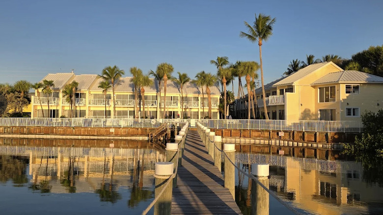 Beautiful view of exterior of Jupiter Waterfront Inn at Golden Hour from the pier with water and palm trees