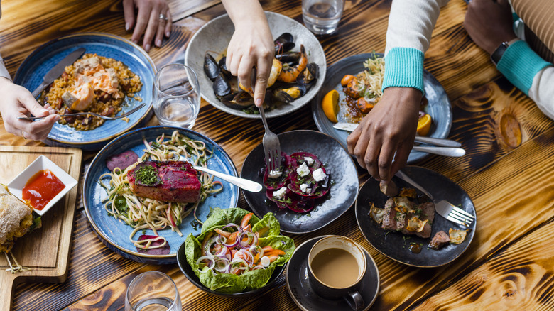 Different plates of food on a table with people eating