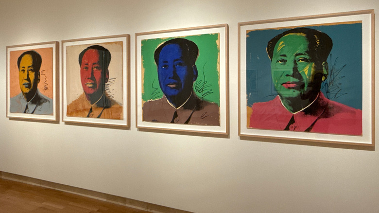 Paintings hanging on wall with a people with yellow, red, blue, and green faces