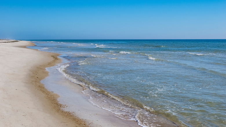Calm blue waves lap a deserted white sand beach on St. George Island, Florida.